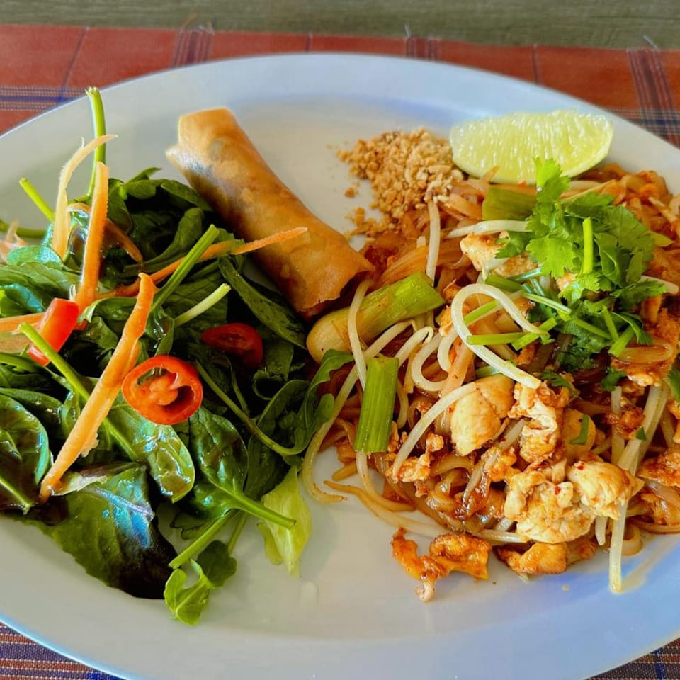 Thai E-San Pad Thai with chicken, bean sprouts, lime, peanuts, spring roll, and side salad.
