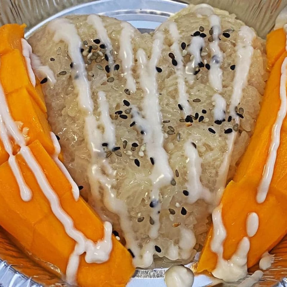 Heart-shaped mango sticky rice with coconut cream and sesame seeds, a Thai E-San dessert.