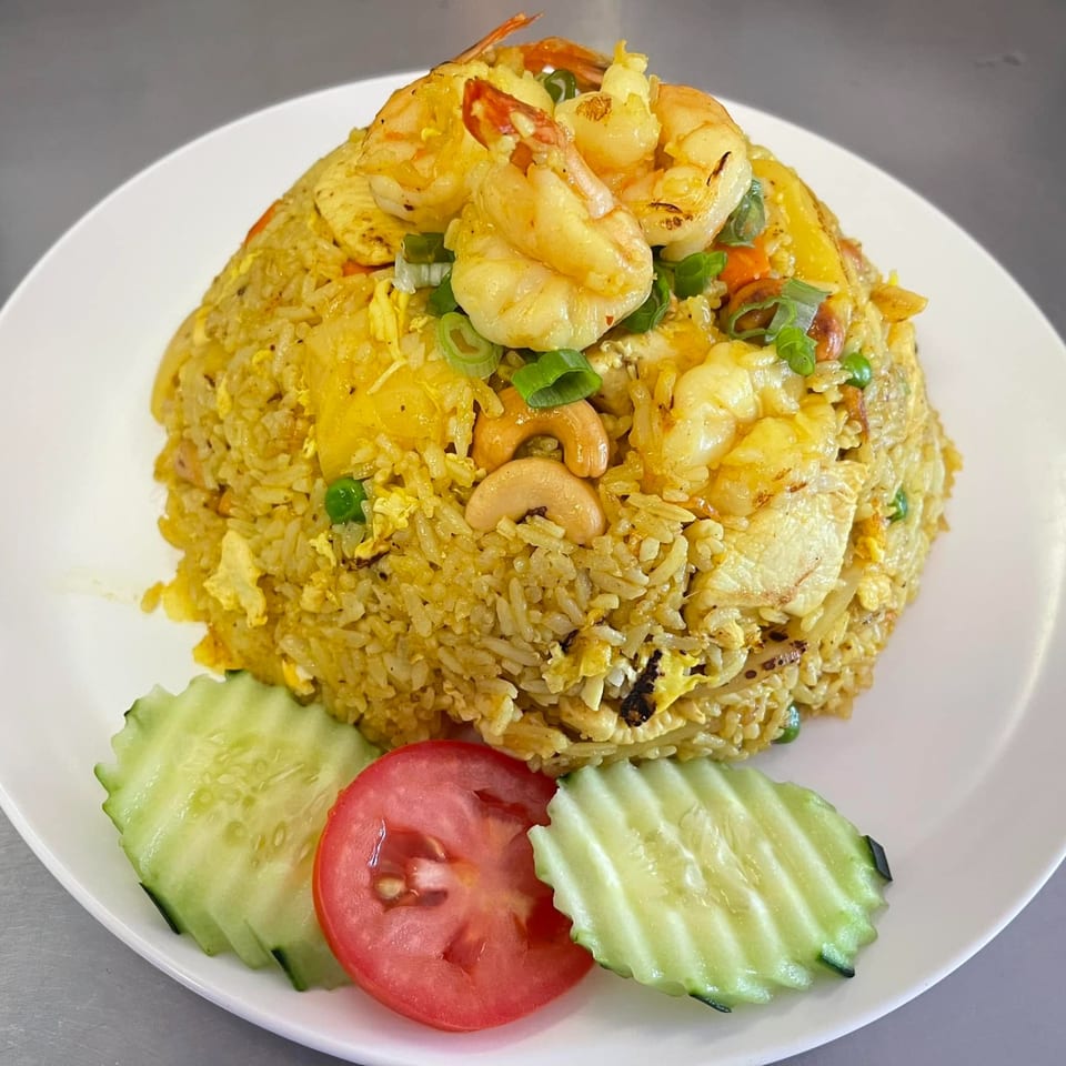 Thai E-San's pineapple fried rice with shrimp, cashews, and vegetables, garnished with cucumber and tomato.